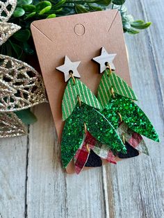 green and red christmas tree earrings with stars on them, sitting next to a holiday ornament