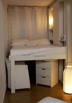 a small bedroom with a bed and desk underneath it