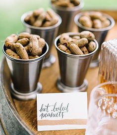 there are several cups with nuts in them on the table next to a card that says hot boiled peanuts