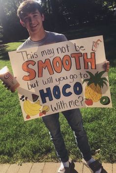 a boy holding a sign that says, this may not be smooth but will you go to hoco with me?