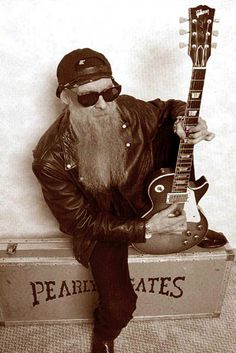 an old photo of a man with a beard holding a guitar and posing for the camera