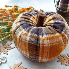 a plaid pumpkin sitting on top of a table next to fall leaves and other decorations