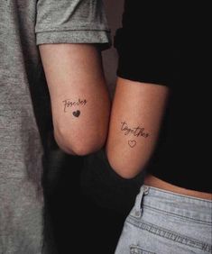 two people with matching tattoos on their arms, one has the word together and the other has