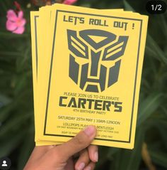 a hand holding up some yellow paper with a transformer mask on it's back