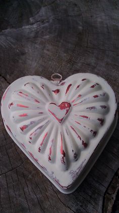 a heart shaped cake pan sitting on top of a piece of wood with blood splattered all over it