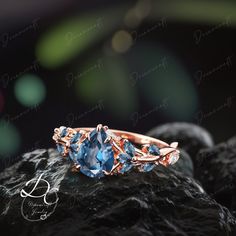 an engagement ring with two blue stones on top of it, sitting on a rock