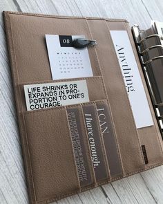 a brown leather binder with notes attached to it and a pen in the pocket