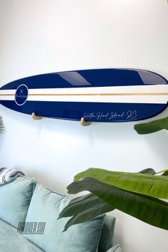 a blue and white surfboard mounted to the wall next to a green plant in a living room