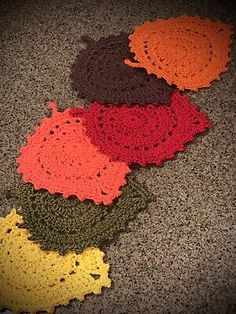 four crocheted doilys laid out on the floor in different colors and sizes