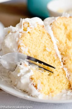 a piece of cake with white frosting on a plate and a fork next to it