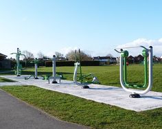 a row of green and white exercise equipment in a park