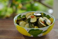 a bowl filled with sliced cucumbers on top of a wooden table