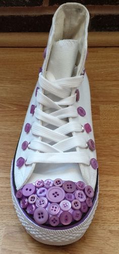 a pair of white shoes with purple buttons on them