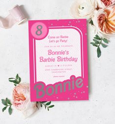 a pink and white birthday card with flowers on the side, next to a roll of toilet paper