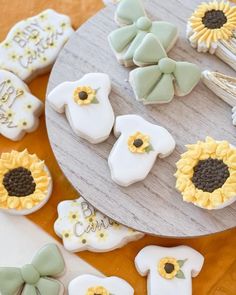 sunflower decorated cookies sitting on top of a wooden table next to utensils