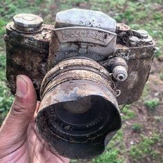 an old camera is being held up in the air by someone's left hand