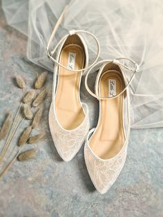 two pairs of wedding shoes sitting on top of a table next to some dried flowers