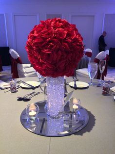 the centerpieces on this round table are made from glass and red rose petals