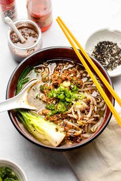 a bowl filled with noodles and vegetables next to chopsticks