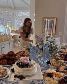 a woman standing in front of a table filled with cakes and pastries on it