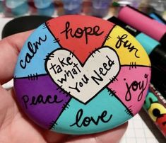 a hand holding a colorful pin with writing on it that says hope, love, make what you need, peace, and joy