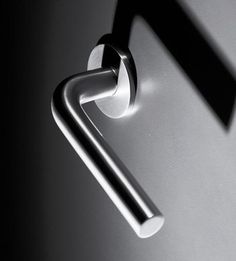 a close up of a door handle on a metal surface with the shadow of an object behind it