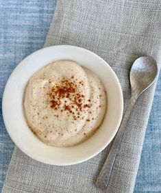 a white bowl filled with food on top of a blue table cloth next to a spoon