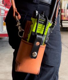 a person holding a cell phone in their pocket with a tool belt attached to it