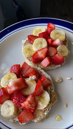 two pieces of bread with strawberries and bananas on top are sitting on a plate