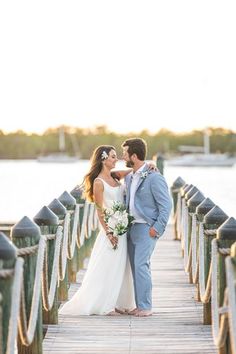 a bride and groom standing on a pier