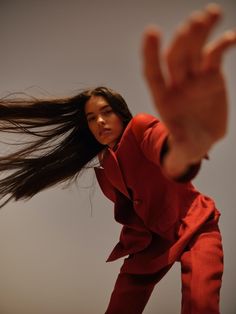 a woman with her hair flying in the air while wearing a red jacket and pants