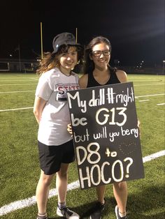 two girls standing on a football field holding a sign that says, my dill might be g13 but will you berry do hoco?