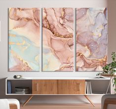 three paintings are hanging on the wall next to a sideboard in a living room