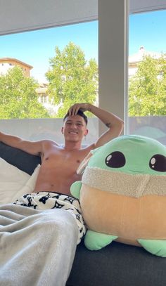 a man laying in bed next to a large stuffed animal turtle on top of a pillow