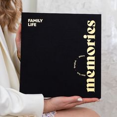 a woman holding up a book that says,'family life'in gold lettering