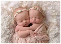 two newborn babies cuddle together on a blanket