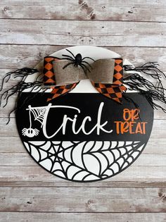 a trick or treat sign hanging on the side of a wooden wall with spider webs