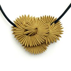 a gold necklace is shown on a black cord and has an intricate design in the shape of a sunburst