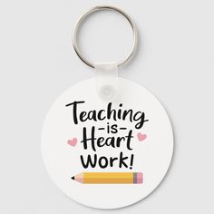 a round keychain with the words teaching is heart work written on it and a pencil