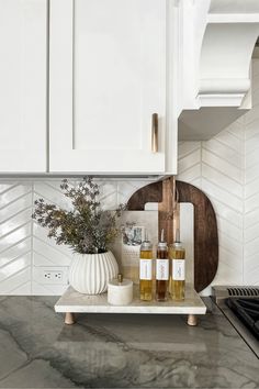 a kitchen with white cabinets and marble counter tops, including soap dispensers