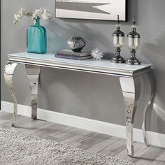 a console table with two vases and books on it in front of a gray wall