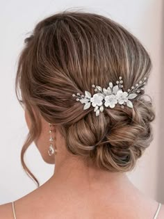 a woman wearing a bridal hair comb with flowers on it's head and pearls in her hair