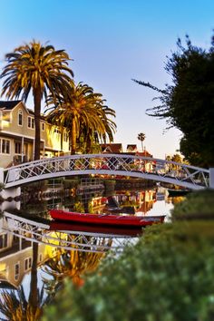 a boat is floating on the water in front of palm trees and houses at dusk