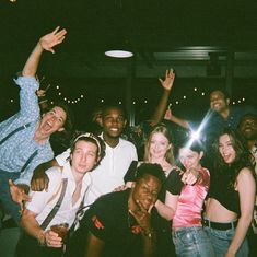 a group of people standing next to each other in front of a building at night