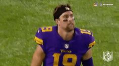 a man in a football uniform standing on a field with his eyes closed and one eye partially open