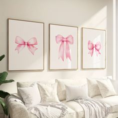 three pink bows are hanging on the wall above a white couch in a living room