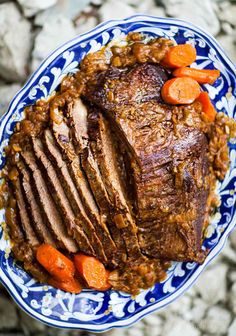 a blue and white plate topped with meat and carrots