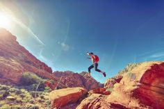 a man is jumping off rocks into the air on a sunny day in the desert