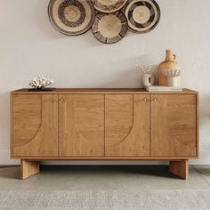 a wooden sideboard with baskets hanging on the wall