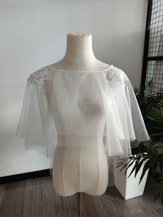 a mannequin wearing a white top with sheer sleeves